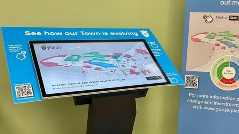 Government of Jersey A touch screen with a 3D map of St Helier on it. The screen has a border which reads: See how our town is evolving.