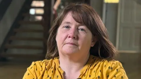 A woman with brown hair wearing a yellow blouse