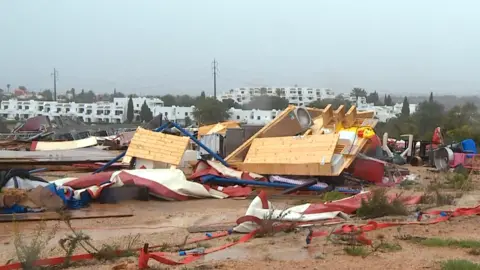 Debris from the storm-hit campsite lies on the ground below a grey sky