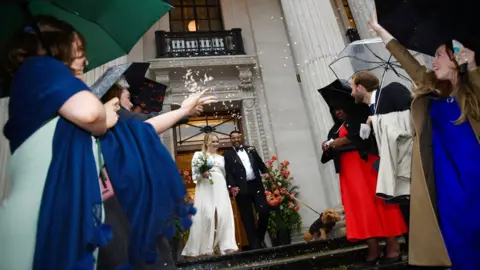 Emma Lynch / BBC Daisy McDonnell and Dan McKinley with their dog Marvin leave the town hall