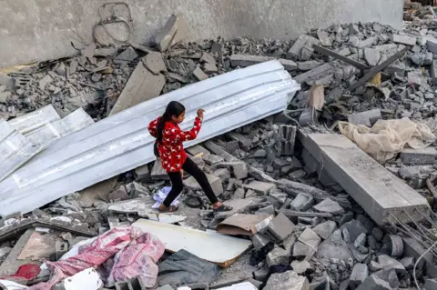 AFP A girl walks through rubble in Rafah in the southern Gaza Strip on 24 April 2024