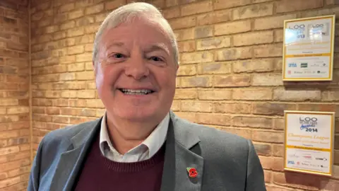 BBC Councillor Alan Amos is standing inside a council building.