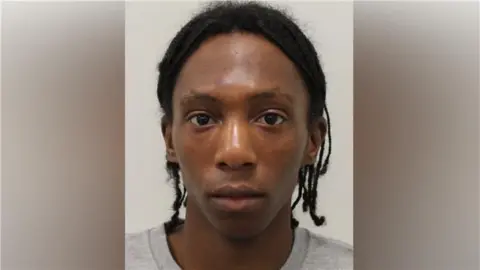 Met Police Mugshot of Shakeil Thibou. He is seen from the shoulders up wearing a grey top.