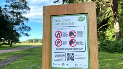 A public Public Spaces Protection Orders sign in the New Forest on a sunny day.