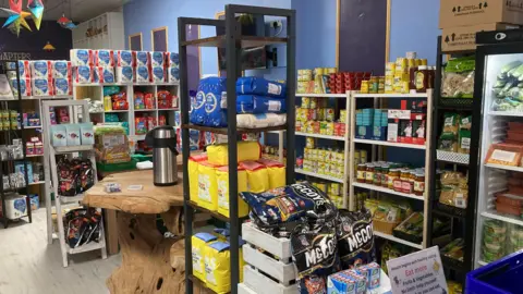 Shelves full of canned and packet foods, as well as cleaning products.