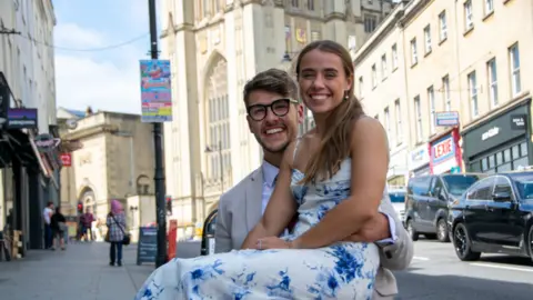 PA Media/University of Bristol Kirsty sat on Zander's lap as they both smiled in a street outside a university building