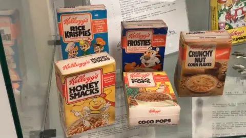 Vintage cereal packaging on display in a cabinet.
