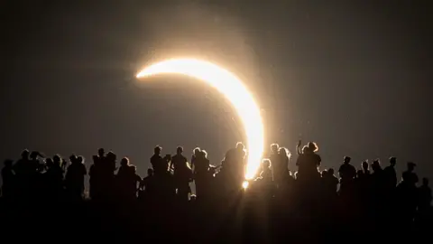 Getty Images People view the partial solar eclipse besides the historic St. Michael's Church tower, a Grade I listed building at the top of Glastonbury Tor on August 12, 2026 in Glastonbury, England. 