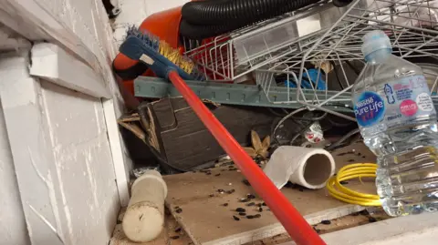 City of Wolverhampton Council Items including a broom, a yellow cable and a water bottle are near to a white wall on the left of the photo. 
