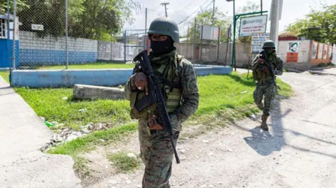 Getty Images PORT-AU-PRINCE, HAITI - MARCH 06: A Haitian soldier stands guard at the entrance to Port-au-Prince international airport after armed gang members exchanged gunfire with police and soldiers around the airport in Port-au-Prince, Haiti on March 06, 2024. 
