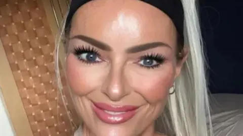 Jennifer Anne Brown has blonde hair and a black headband. She is smiling 