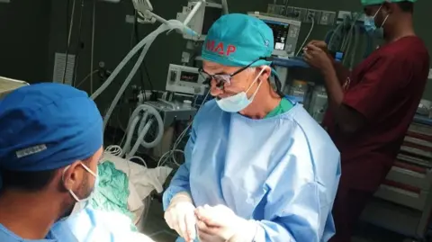 Nizam Mamode Prof Nizam Mamode operates on a patient with an arterial injury after a bombing, with a Palestinian surgeon assisting