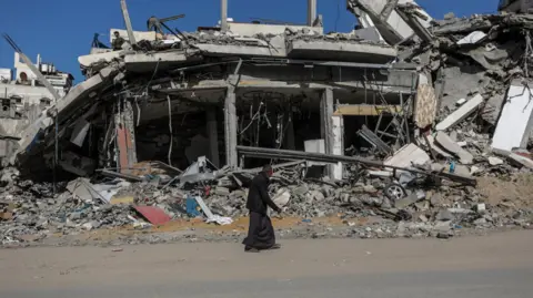 EPA is an elderly Palestinian man walking through a devastating building in Gaza City