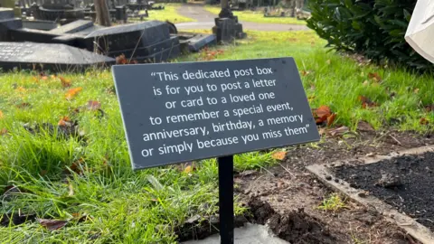 A black plaque at Nottingham Road Cemetery that reads: "This dedicated post box is for you to post a letter or card to a loved one to remember a special event, anniversary, birthday, a memory or simply because you miss them."