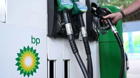 Close up of petrol and diesel pumps and hand on one of the pumps with the BP logo to the side