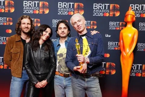 PA Media Wolf Alice hold their award up to the camera.
