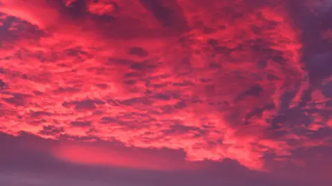 BBC Weather Watchers / Ingrid Clouds in the sky appear pink and purple.