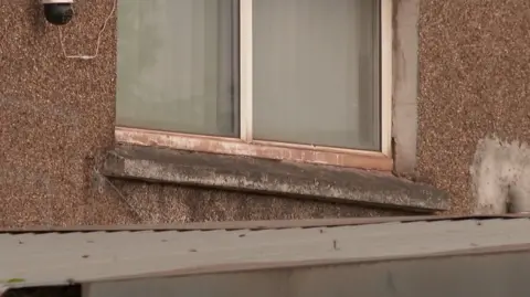 A once white exterior windowsill is covered in black dust