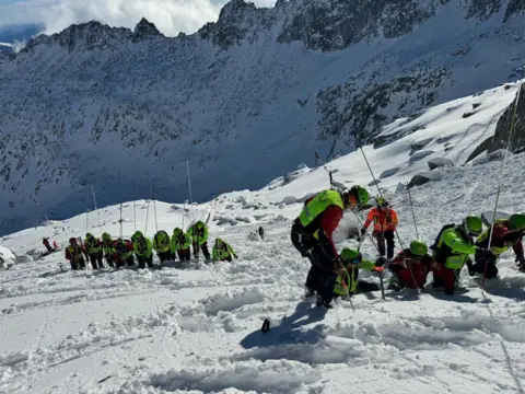 Soccorso Alpino e Speleologico Trentino Rescuers on the mountain carry out a fingertip search on the snow