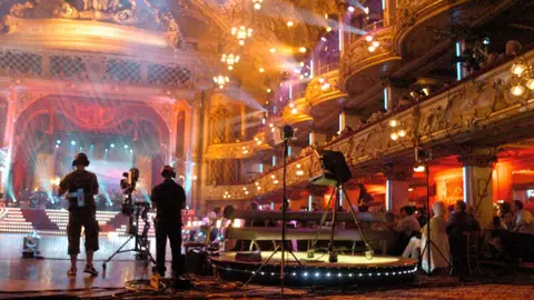 Camera crew filming in Blackpool's Tower Ballroom. The audience is looking on.