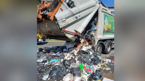 A bin lorry emptying household waste onto a Southampton street.