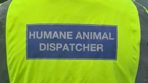 Hampshire and Isle of Wight Constabulary A Humane Animal Dispatcher's hi-vis jacket, that says "Humane Animal Dispatcher" in white letters on a blue background 