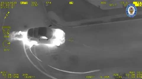 West Midlands Police Black and white police video showing a car driving so fast its engine is white hot, with tyre marks burned into the road