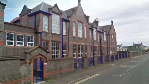 Google The former school on Park Road, a red and brown building, with blue railings, the school looks run down.