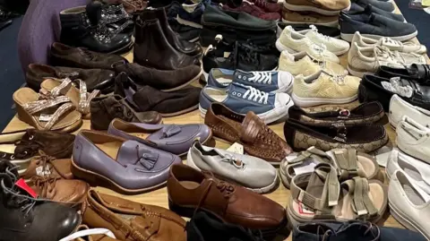 A table covered in pairs of men and womens shoes