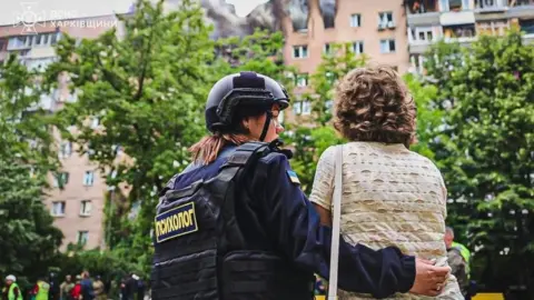 A handout photo released by the press service of the State Emergency Service (SES) of Ukraine shows a psychologist providing assistance near the site of an air strike in Kharkiv, northeastern Ukraine, 07 June 2025