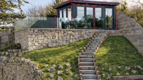 Glass cabin in a garden with a balcony surround
