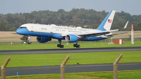 PA Media Air Force Two, a blue and white airplane landing on tarmac. It says United States of America and has the American flag painted on the tail 