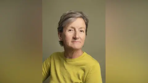 Supplied Sarah Hendrickx. She has short grey hair and brown eyes. She is wearing an acid green jumper and looking at the camera with a slight smile.
