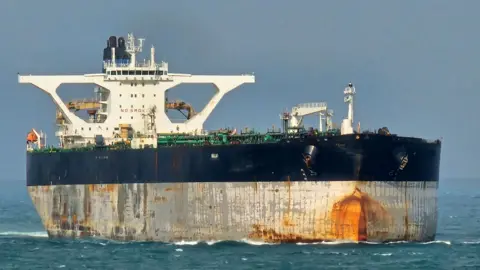 Reuters The tanker is a large ship with white bridge and a black and white hull. The part of the boat nearest the surface of the sea has large rusty marks on it.