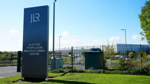 Getty Images A large grey sign saying 'JLR Electric Propulsion Manufacturing Centre' stands in front of the gates enclosing the JLR factory in Wolverhampton.
