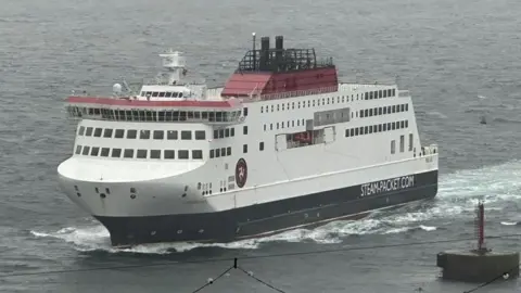 The Manxman ferry, which is in the Isle of Man Steam Packet Company's colours of red, white and black, sailing in Douglas Harbour on an overcast evening.