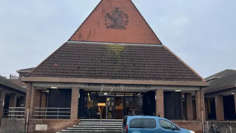 Guildford Crown Court, which is a low-rise brick building with a very large, oversized, pointy roof.