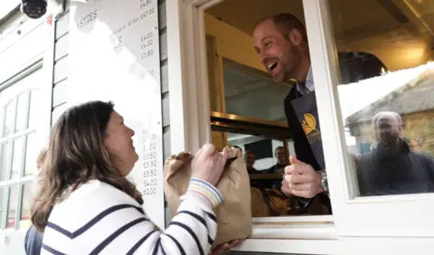 PA Media The Prince of Wales, known as the Duke of Cornwall while in Cornwall, serving customers during his visit to the Gear Farm Pasty Company.