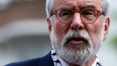 PA Media A close up of Gerry Adams. He has grey hair and beard, and is wearing tan circular glasses and is speaking.
