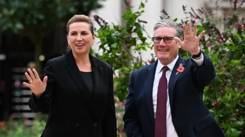 EPA Danish Prime Minister Mette Frederiksen and British Prime Minister Keir Starmer, both are smiling and waving.