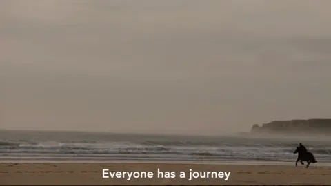 Green Eye Productions A shot from Lé Viage with a horse running along the beach at St Ouen's Bay. Subtitles say: "Everyone has a journey."