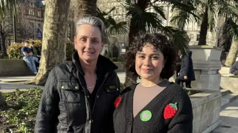 Kate Osborne MP (left) stands with Myranda Flores outside the Houses of Parliament.
