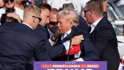 President Trump helped by Secret Service agents to leave Pennsylvania rally