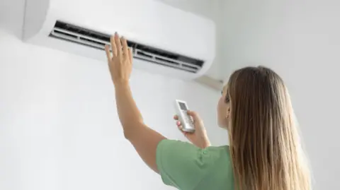 A woman switching on her air conditioning