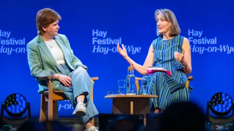 PA Media Two women in conversation while seated on a stage in front of an audience