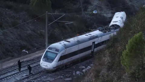 Members of the Spanish Civil Guard work next to one of the trains involved in the accident