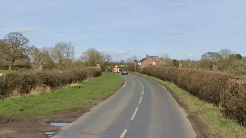 A country road lined with hedges and green verges