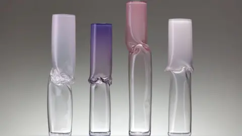 Simon Bruntnell Four glass cylinders which are slightly twisted and deformed in the middle. All four cylinders are different shades of pink/purple on the top half, but clear at the bottom. 