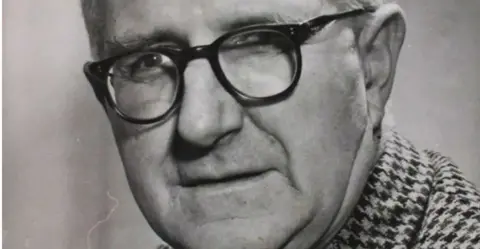 Frank Falla Archive Frank Falla wearing dark rimmed glasses and a check jacket