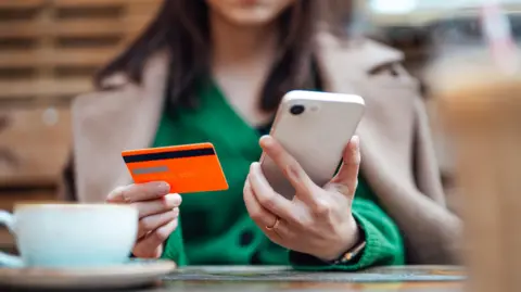 Getty Images Woman using mobile banking app while in a cafe